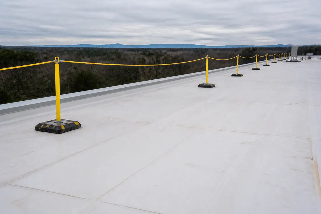 A warning line on stanchions running parallel to the edge of a low-slope commercial roof