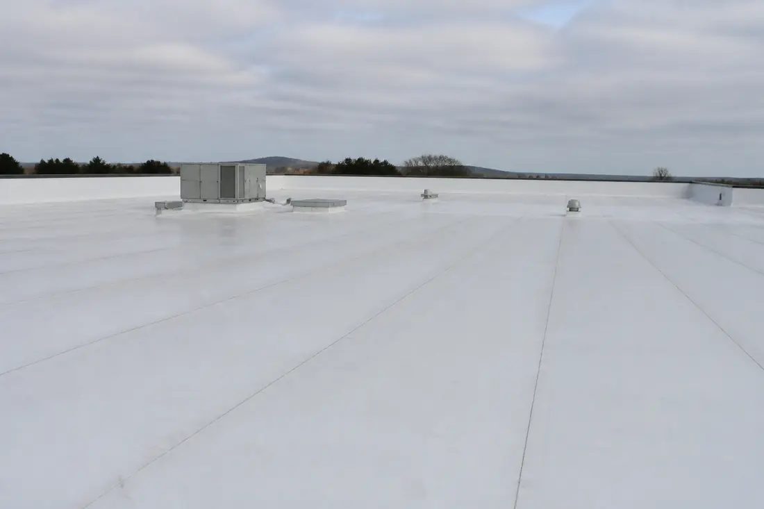 A single-ply membrane roof on a commercial building with welded seams running across it